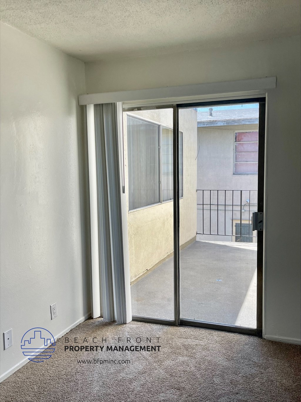 an empty room with a sliding glass door to a balcony